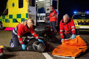 emergency team assisting injured motorbike man driver at night
